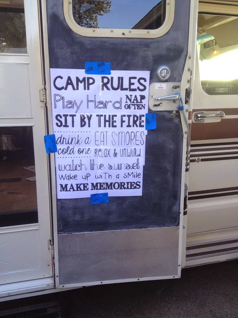Chalkboard painted on the RV door with a stencil of "camp rules play hard nap often sit by the fire drink a cold one eat s'mores relax and unwind watch the sunset wakeup with a smile make memories" 