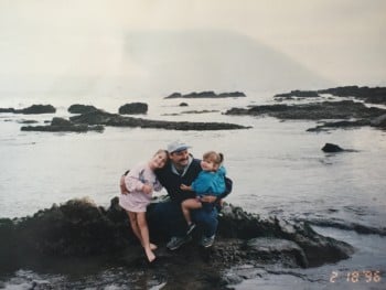 Carpinteria 1996 a dad and 2 girls sitting on rock next to ocean