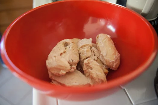 Chicken, bullion cubes, and water in a red bowl 