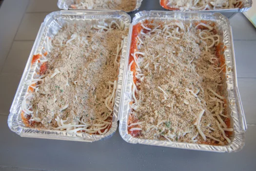 Shredded chicken, red sauce, mozzarella cheese and breadcrumbs in two containers  