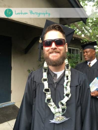 Finished money lei chain around man wearing black graduation gown 