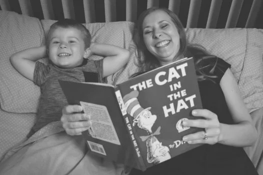 Mom with son on bed reading cat in the hat book