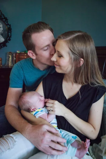 Picture of man kissing woman's cheek holding their baby 