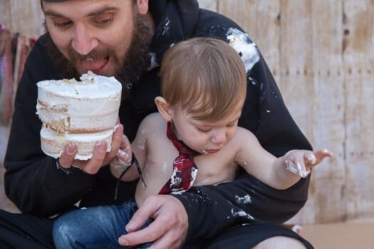 Dad eating white cake with toddler boy 