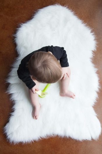 baby sitting on white fur blanket, photo taken from above