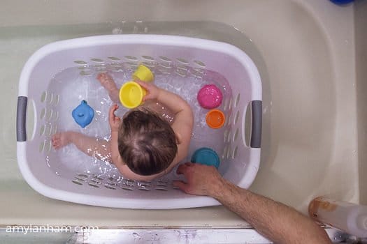 Toddler Bath time Hack with baby in laundry basket in bath 