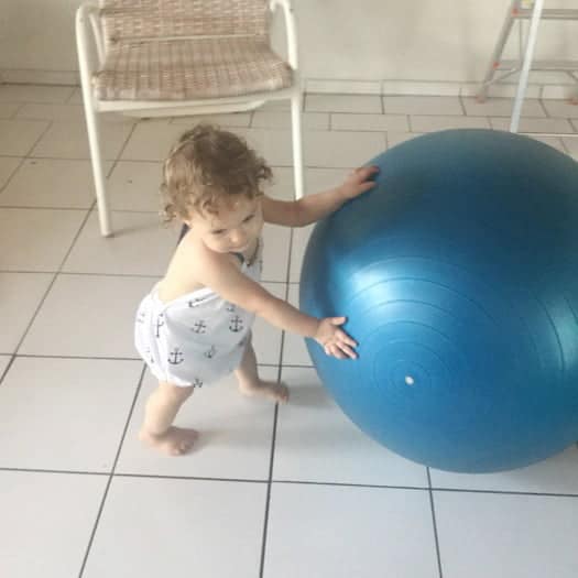 Toddler playing with big blue bouncy ball