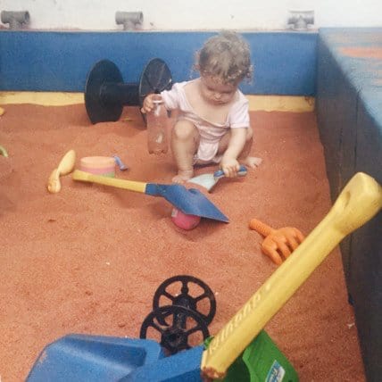 Toddler playing in a sandbox with toys