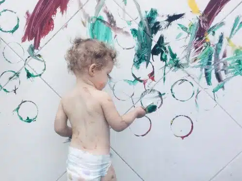 Toddler playing with textures on wall