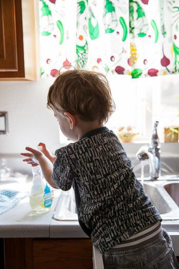 Toddler standing on Ikea tower using soap 