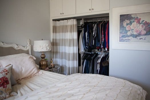 DIY Closet Organization in bedroom with bed and lamp on side table 