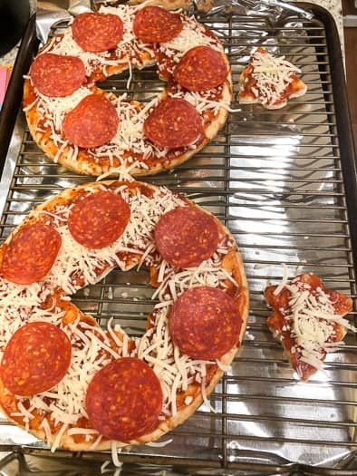 pizzas with Christmas tree cut out in middle with cheese and pepperoni on baking sheet 
