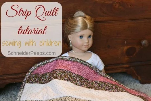 Strip quilt tutorial sewing with children. strip quilt on floor laying on a doll with blonde hair blue eyes leaning up against wood dresser.