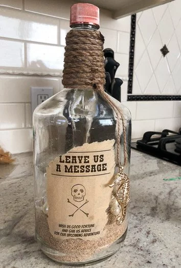 Pirate styled titos vodka bottle with sand in it and leave us a message sign