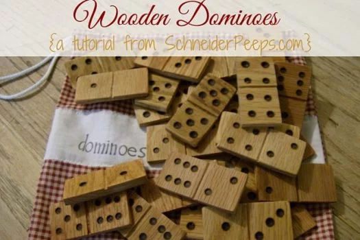 A Pile of Wooden Dominoes laying on a red checkered pattern bag with word dominoes on it laying on a wood table