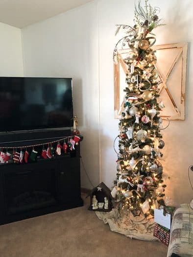 thin faux Christmas tree decorated next to TV on stand 