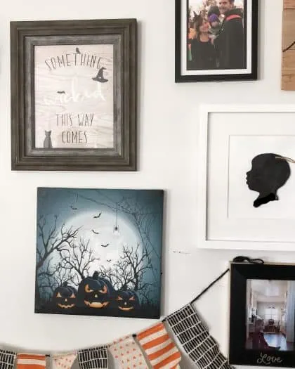 A picture frame labeled something this way comes printable. Halloween themed hanging. A picture of a couple. A banner all hanging on the wall. 