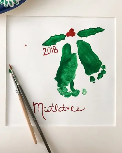 Green color painting of toddler feet with mistletoe above it from 2018