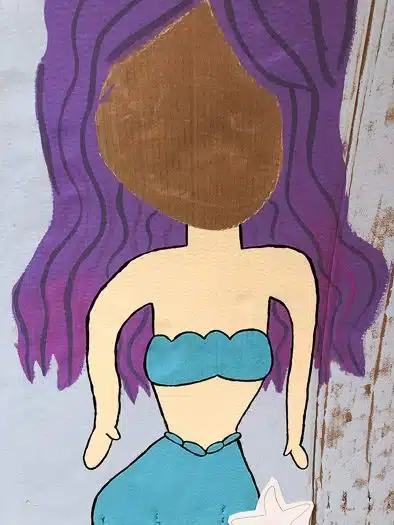 Painted in chalk drawing of mermaid with purple hair and blue bikini