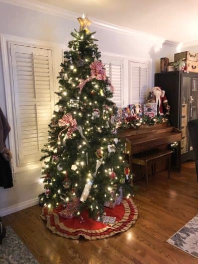 Christmas tree decorated next to piano