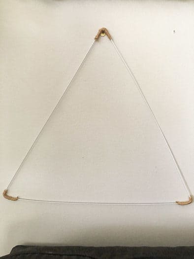 Triangle wire with twine wrapped corners hanging on wall