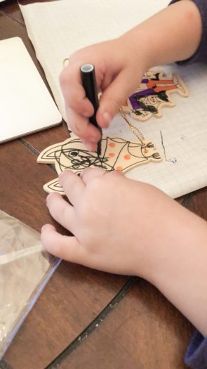 toddler handers drawing with marker on a wooden bat ornament