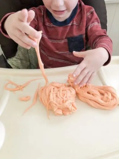 toddler playing with orange gooey slime