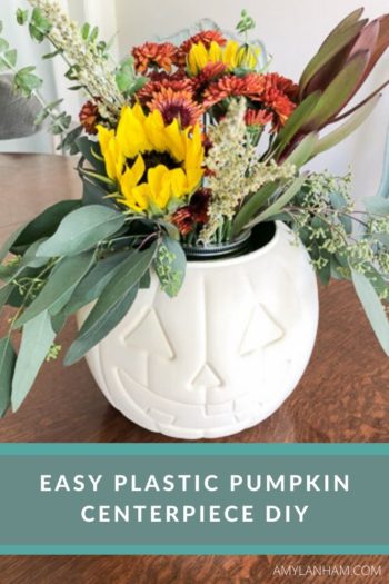 Easy plastic pumpkin centerpiece DIY text overlaid on an image of a white pumpkin with red and yellow flowers sticking out of it.