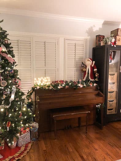 piano with lighted noel sign and Santa next to Christmas tree