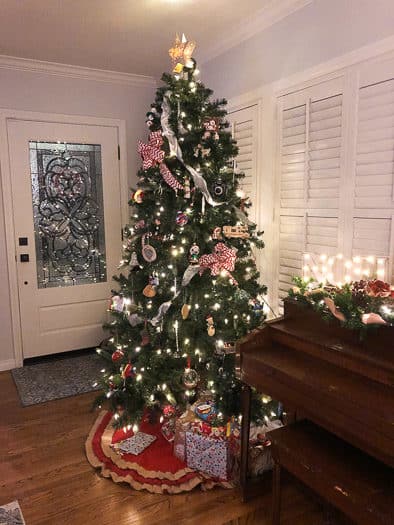 Christmas tree next to piano with lighted Noel sign