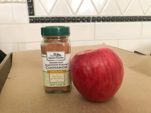 Apple and a bottle of cinnamon next to it