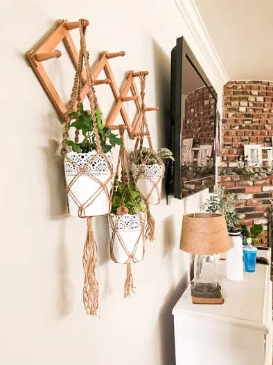 Macrame plant hanger on wall next to tv and dresser