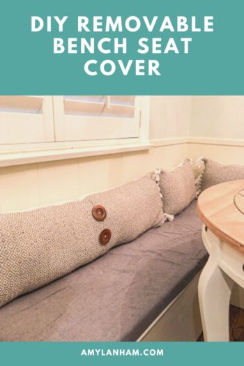 DIY Removable Bench Seat Cover pin, white bench with grey cushion on bench, and tan pillows with wooden buttons.