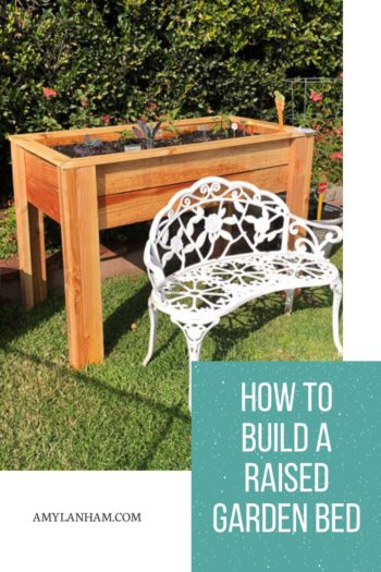 How to build a raised garden pin - waist high raised wooden garden bed with veggies growing and a white bench in front