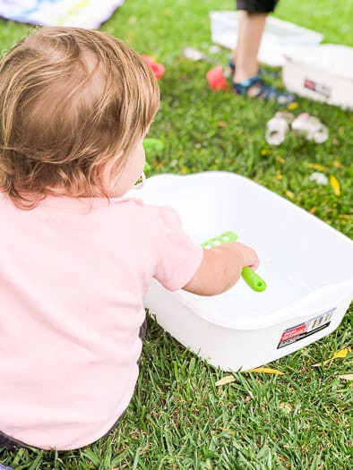 Toddler in pink playing with toy in bin