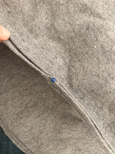 Showing a close up of a pin in the grey fabric