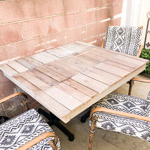 Square pallet table outside with three chairs surrounding