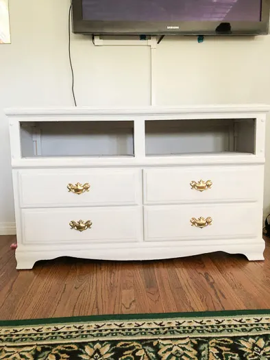 A white dresser with the top 2 drawers taken out, gold handles on the bottom 4 drawers.
