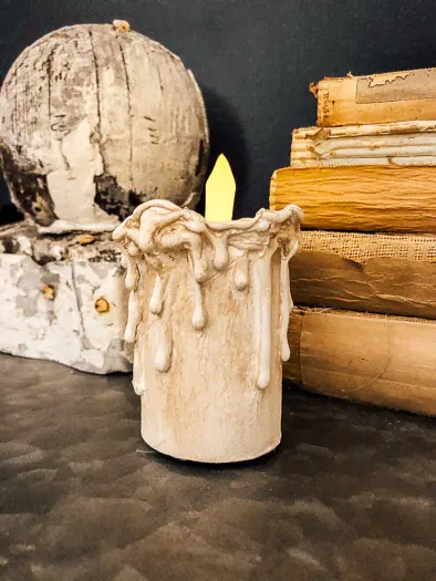 Small toilet paper candle with a fake candle inside, books stacked on the right side.