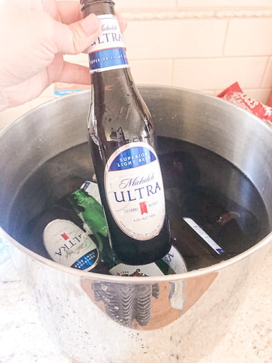 Beer bottles being put in a pot of soapy water