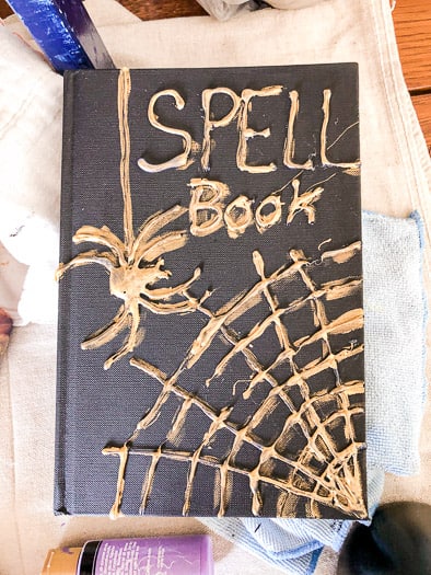 Cover of the book with Spell Book and a spider and web in hot glue covered with gold paint
