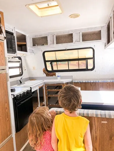 Two kids looking at the primed cabinets