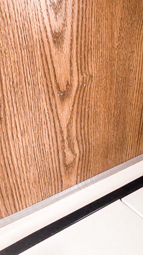Close up of a wooden wall with tiny white specs on it.