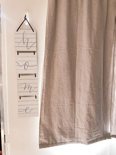 Home sign hanging to the left of a curtain
