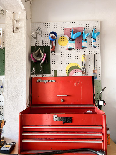 Tools hanging on a pegboard with a snap on tool box sitting in front of it