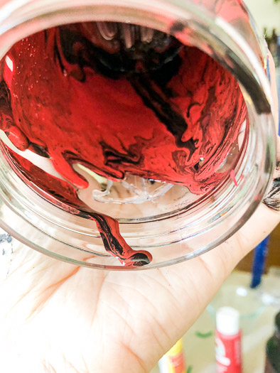 Black and red paint dripping inside of a jar
