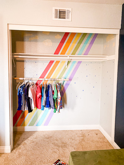 rainbow wall in a closet with a low rod and kids clothes hanging