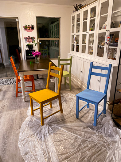 colorful chairs around a table with plastic on the floor