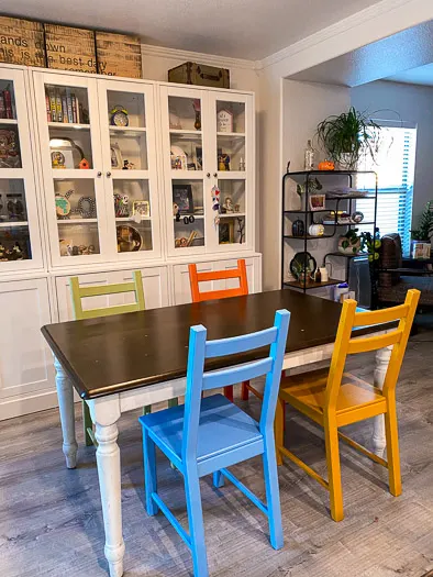 blue, yellow, orange, and green chairs around table with cabinets in the background