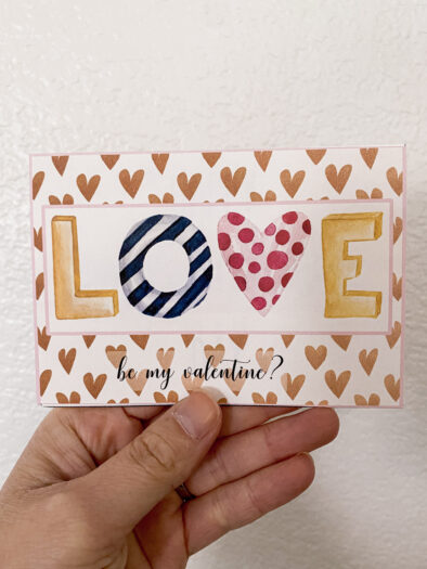 hand holding a post card that says love be my valentine?